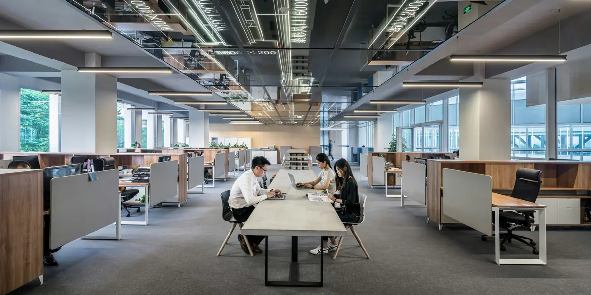 A bright open-plan office, with three people working at a long shared table