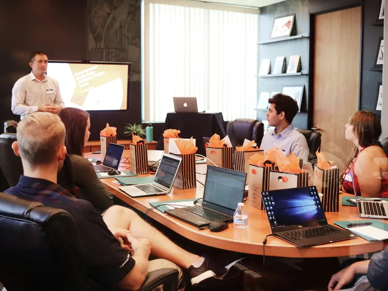 A consultant leads a project session while the team follows along on laptops